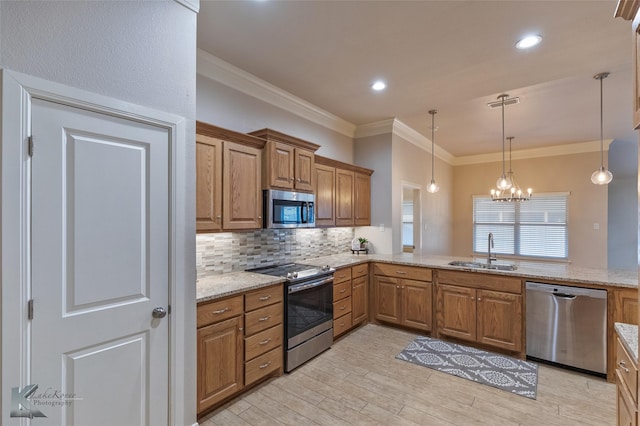 kitchen featuring sink, an inviting chandelier, light stone counters, pendant lighting, and appliances with stainless steel finishes