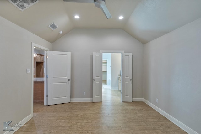 unfurnished bedroom featuring a walk in closet, vaulted ceiling, ceiling fan, light wood-type flooring, and a closet