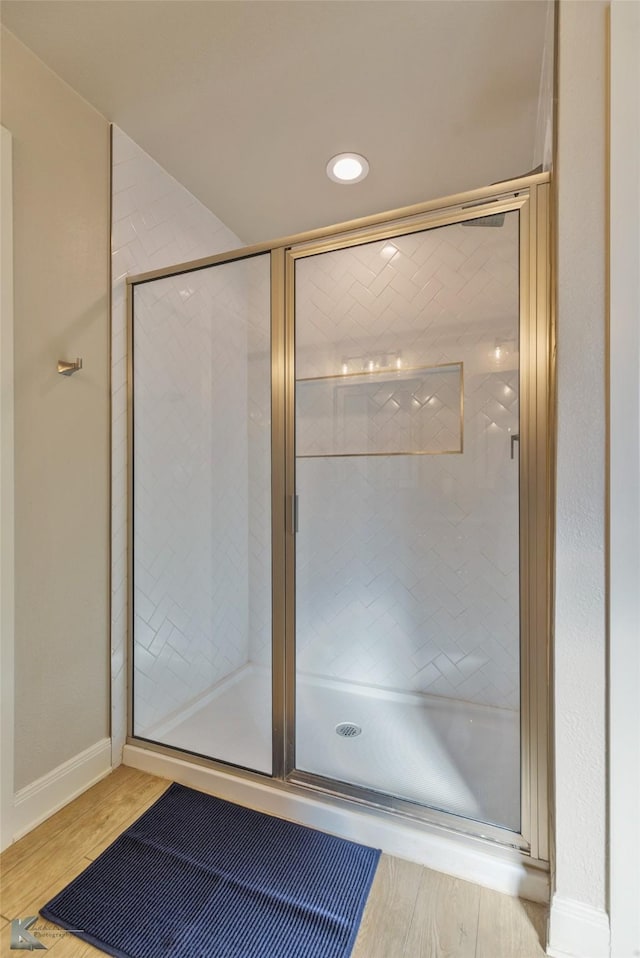 bathroom with hardwood / wood-style floors and a shower with shower door