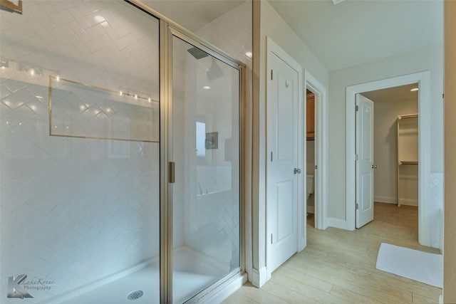 bathroom with hardwood / wood-style floors and a shower with shower door