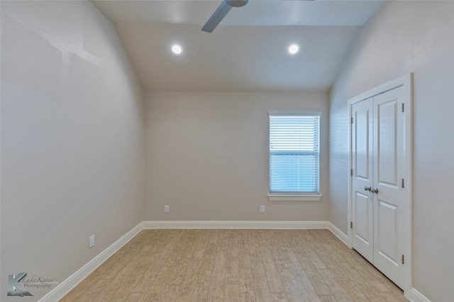 spare room with light wood-type flooring, vaulted ceiling, and ceiling fan