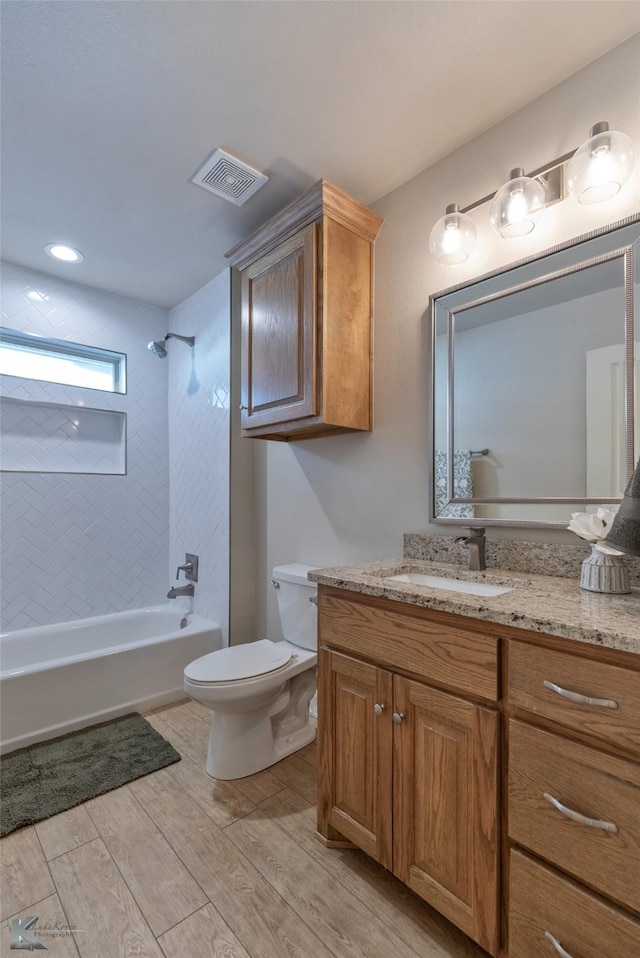 full bathroom with vanity, toilet, wood-type flooring, and tiled shower / bath