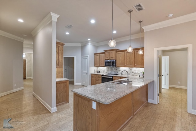 kitchen featuring light stone countertops, appliances with stainless steel finishes, sink, pendant lighting, and light hardwood / wood-style floors