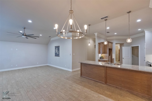 kitchen featuring sink, crown molding, hanging light fixtures, light wood-type flooring, and light stone countertops