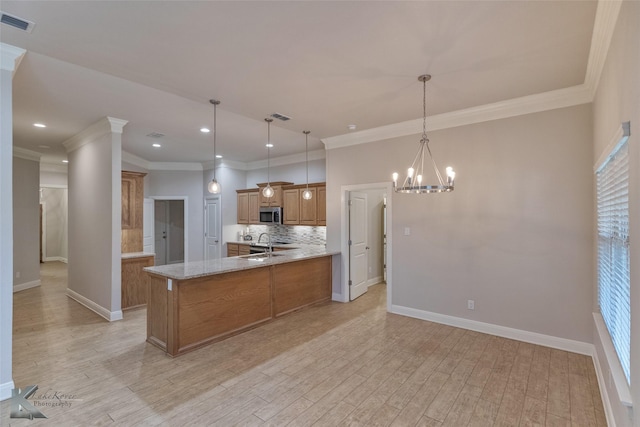 kitchen with decorative light fixtures, light hardwood / wood-style flooring, and a healthy amount of sunlight