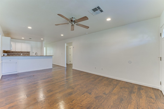 unfurnished living room featuring dark hardwood / wood-style floors, ceiling fan, and sink