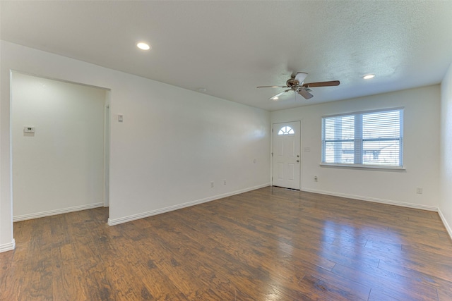 spare room featuring dark hardwood / wood-style floors, ceiling fan, and a textured ceiling