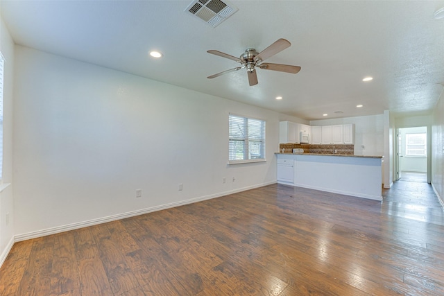 unfurnished living room featuring ceiling fan and dark wood-type flooring