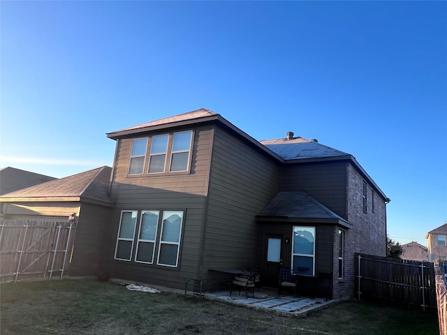 back of house with a lawn and a patio