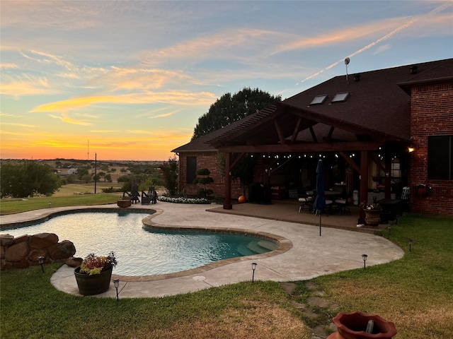 pool at dusk with a patio area and a yard