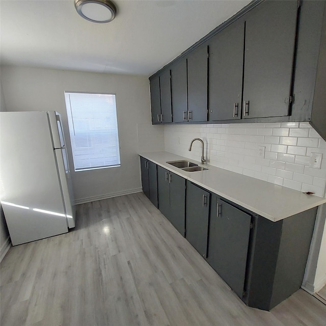 kitchen with backsplash, sink, light hardwood / wood-style flooring, and white refrigerator