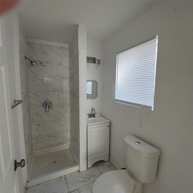 bathroom with a tile shower, vanity, and toilet