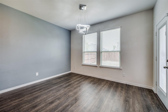 empty room featuring dark hardwood / wood-style flooring and a notable chandelier