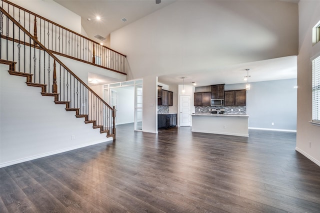 unfurnished living room with dark wood-type flooring and high vaulted ceiling