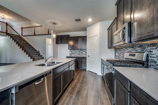 kitchen with sink, dark wood-type flooring, hanging light fixtures, decorative backsplash, and appliances with stainless steel finishes