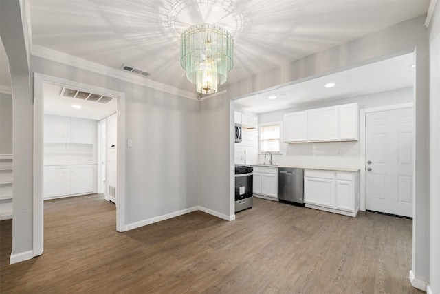 kitchen with appliances with stainless steel finishes, white cabinetry, a notable chandelier, and hardwood / wood-style floors