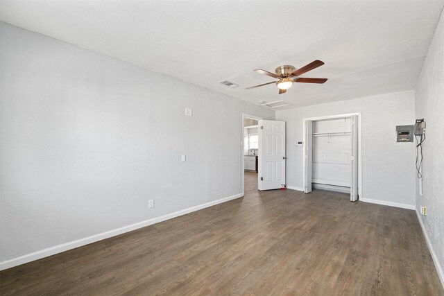 unfurnished bedroom featuring a walk in closet, a closet, dark hardwood / wood-style floors, and ceiling fan