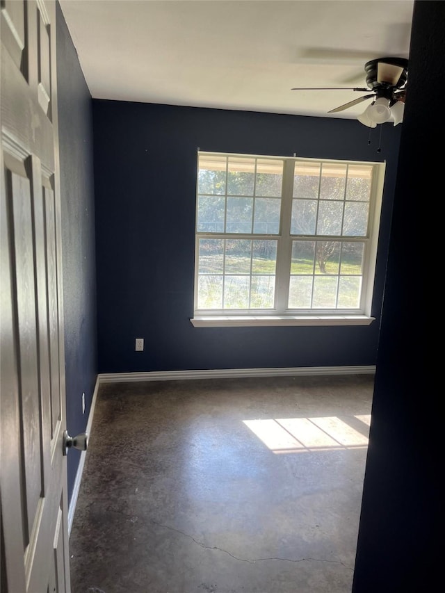 spare room with ceiling fan and concrete floors