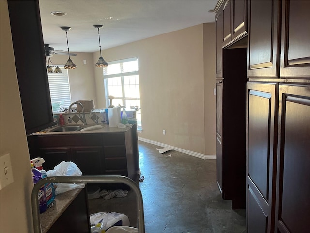 kitchen featuring dark brown cabinetry, sink, and hanging light fixtures