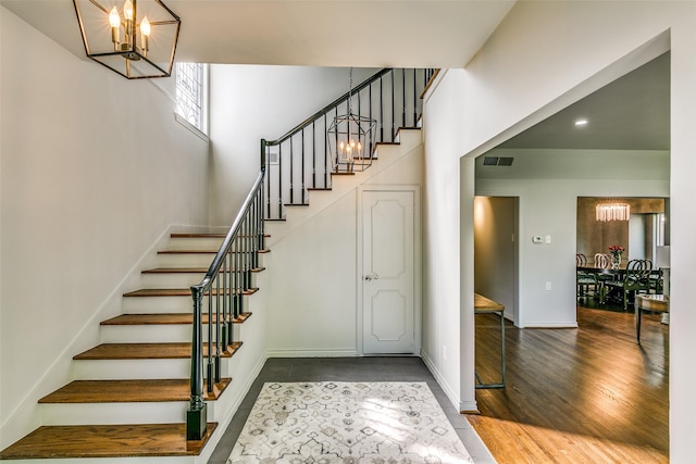 staircase with hardwood / wood-style flooring and a chandelier