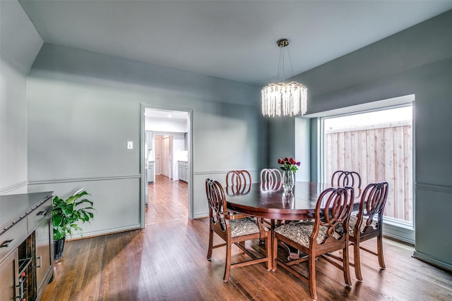 dining space with wood-type flooring and an inviting chandelier