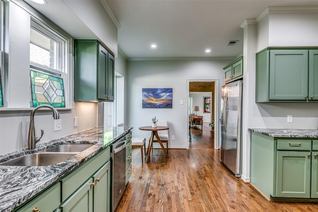 kitchen with hardwood / wood-style floors, green cabinets, sink, ornamental molding, and appliances with stainless steel finishes