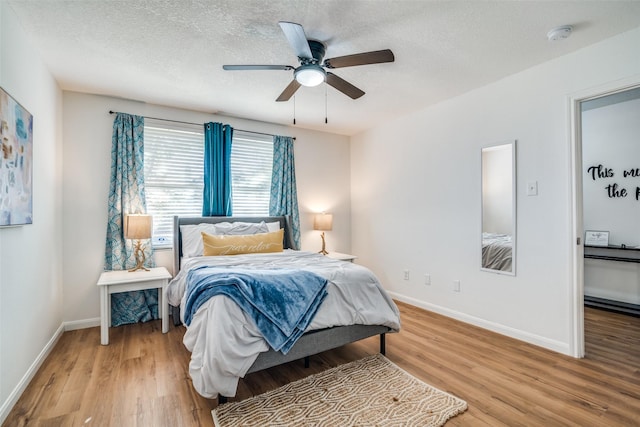 bedroom with hardwood / wood-style floors, ceiling fan, and a textured ceiling