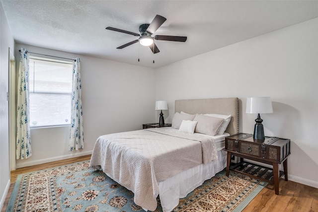 bedroom with a textured ceiling, hardwood / wood-style flooring, and ceiling fan