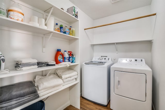 clothes washing area featuring hardwood / wood-style floors and washer and dryer