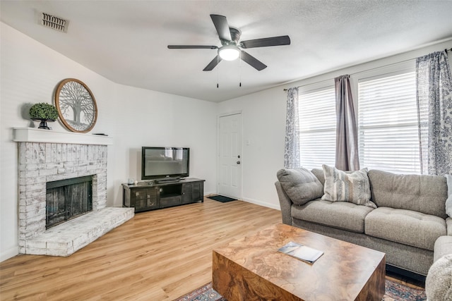 living room featuring a fireplace, ceiling fan, hardwood / wood-style floors, and a textured ceiling