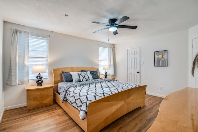 bedroom with a textured ceiling, hardwood / wood-style flooring, multiple windows, and ceiling fan