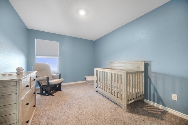 bedroom featuring carpet, a crib, and baseboards