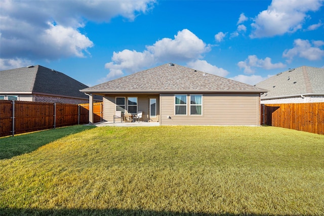 back of property with roof with shingles, a fenced backyard, a lawn, and a patio