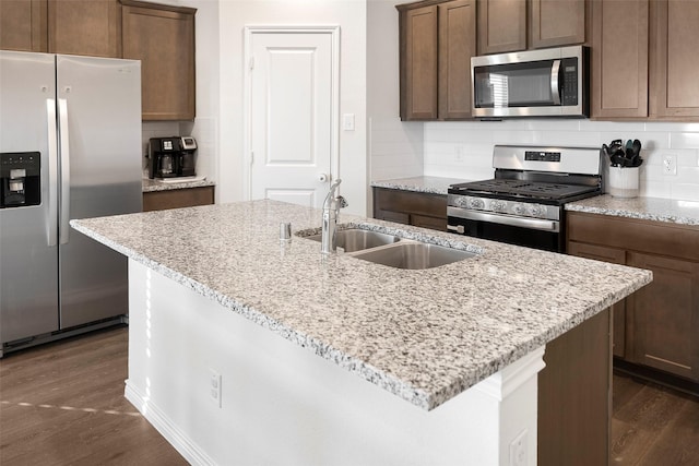 kitchen featuring stainless steel appliances, dark wood-style flooring, a sink, and tasteful backsplash