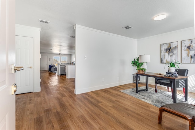 home office with crown molding, wood finished floors, visible vents, and baseboards