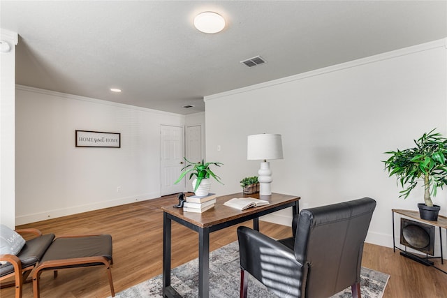 office space featuring visible vents, ornamental molding, baseboards, and wood finished floors