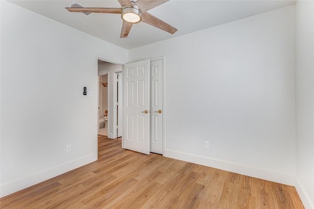 spare room featuring light wood-style flooring, a ceiling fan, and baseboards