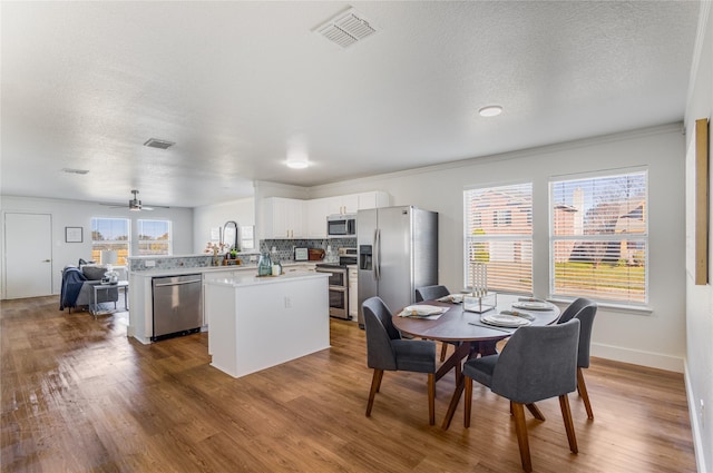 dining area with hardwood / wood-style flooring, ceiling fan, a healthy amount of sunlight, and ornamental molding