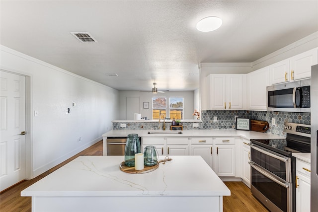 kitchen with appliances with stainless steel finishes, a center island, sink, and white cabinets