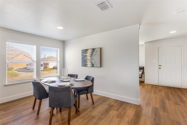 dining area with crown molding and light wood-type flooring