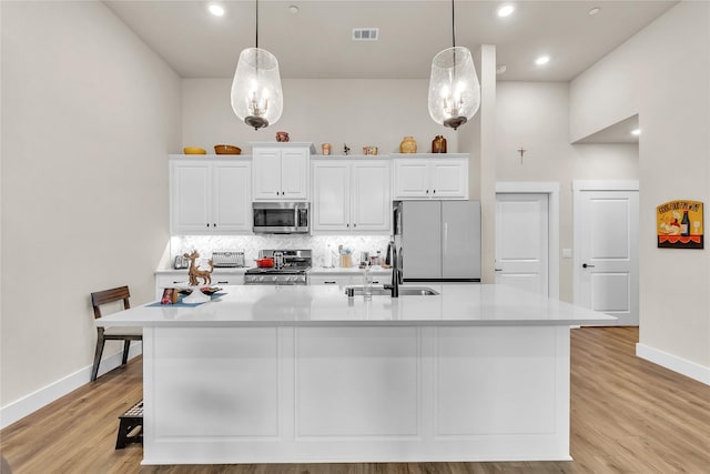 kitchen with stainless steel appliances, sink, and a large island with sink