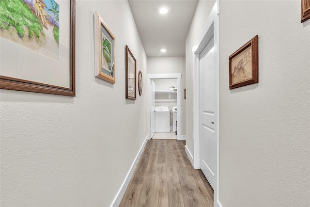 hallway with separate washer and dryer and light hardwood / wood-style floors