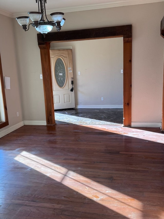 foyer with ornamental molding, dark hardwood / wood-style floors, and a chandelier