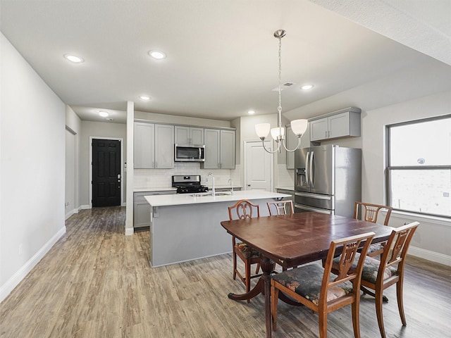 dining area featuring light hardwood / wood-style floors, an inviting chandelier, and sink