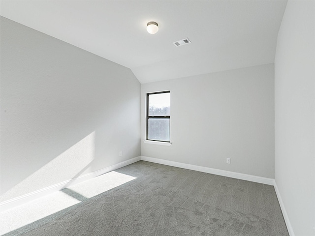 spare room featuring carpet floors and vaulted ceiling