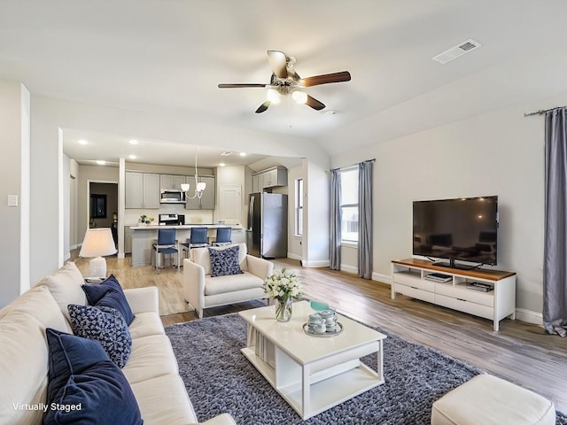 living room with ceiling fan, lofted ceiling, and light hardwood / wood-style flooring