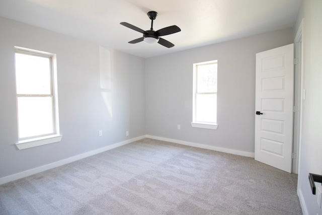 empty room with ceiling fan, light colored carpet, and a wealth of natural light