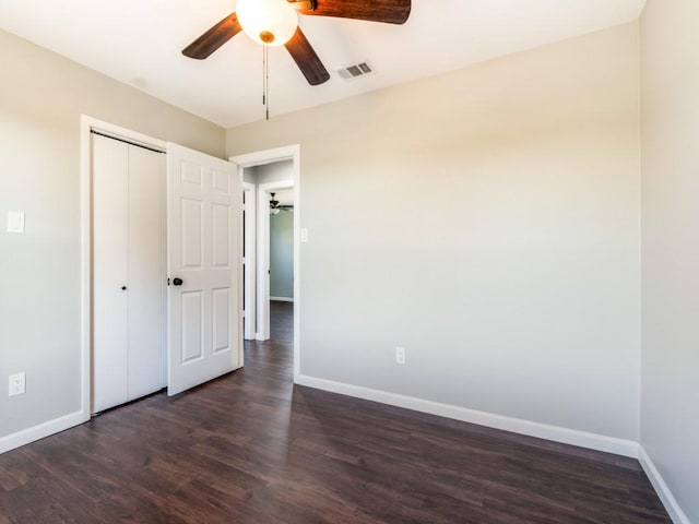 unfurnished bedroom with dark hardwood / wood-style floors, ceiling fan, and a closet