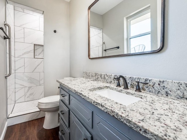 bathroom with tiled shower, vanity, hardwood / wood-style flooring, and toilet