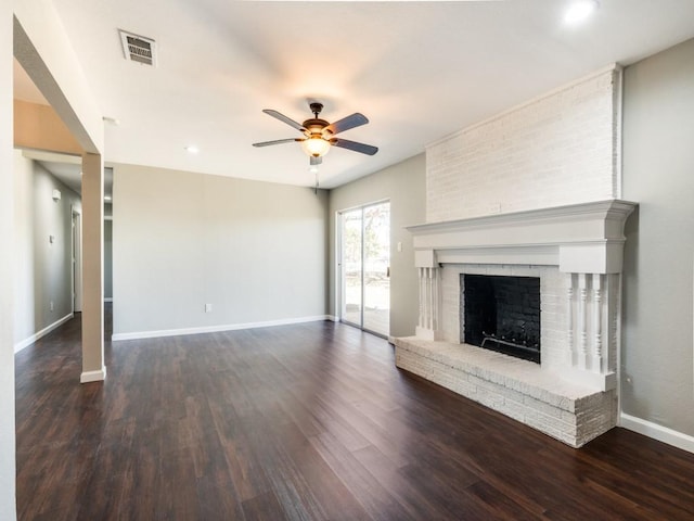 unfurnished living room featuring ceiling fan, dark hardwood / wood-style floors, and a brick fireplace